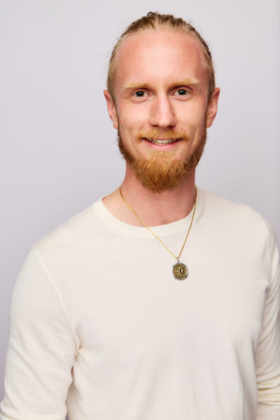 Fredrik Brännlund, founder of Noa The Game Fredrik Brännlund smiling at the camera in a light knitted sweater against a pale lilac backdrop